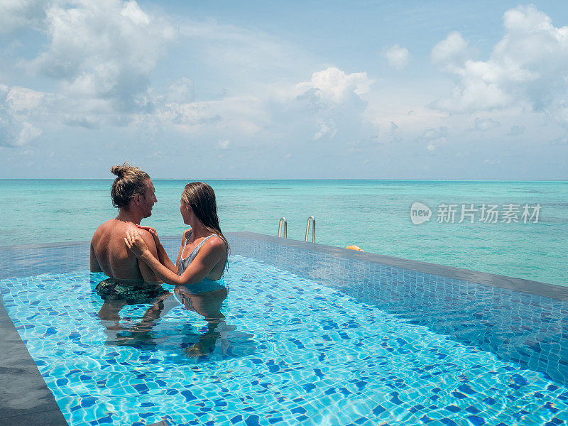 情侣在豪华度假胜地游泳池浪漫的暑假