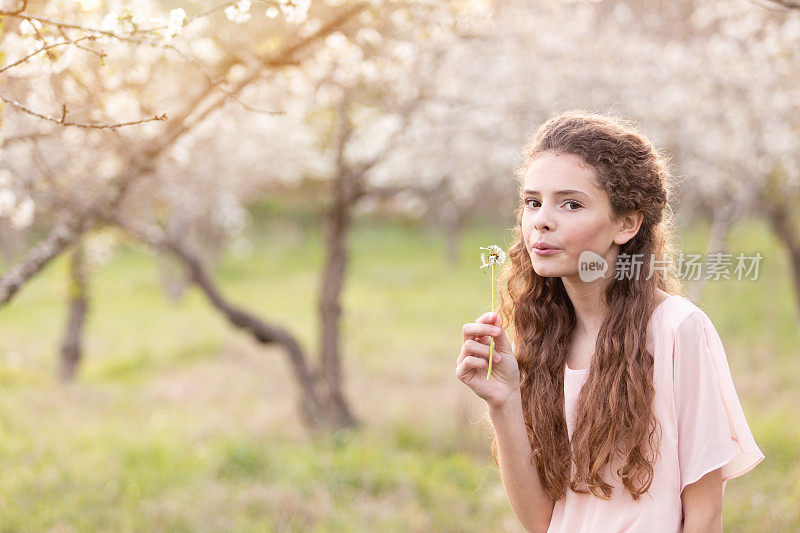 年轻美丽的女孩在春天被樱桃树包围