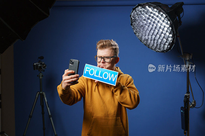 博主用前置摄像头拍摄视频，手里拿着“follow”的牌子，邀请观众订阅他的视频频道和社交网络。