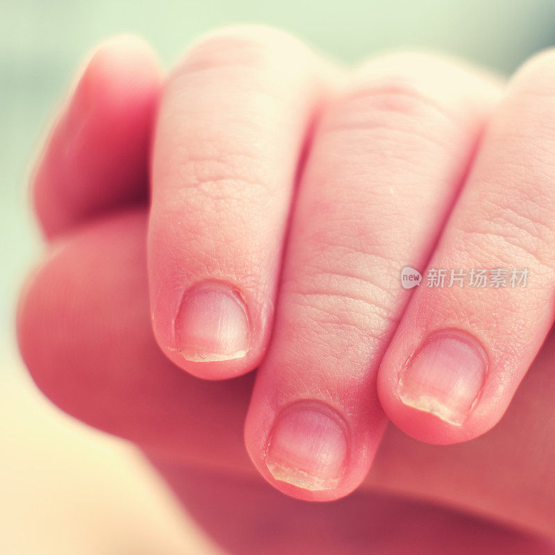 手指放在大人的手上，手指放在新生儿的手上，微距拍照