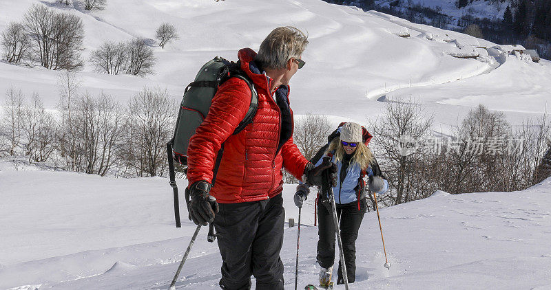 成熟的情侣在野外滑雪爬雪坡