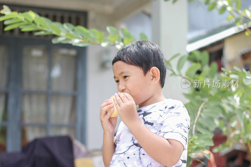 男孩站在前屋吃面包