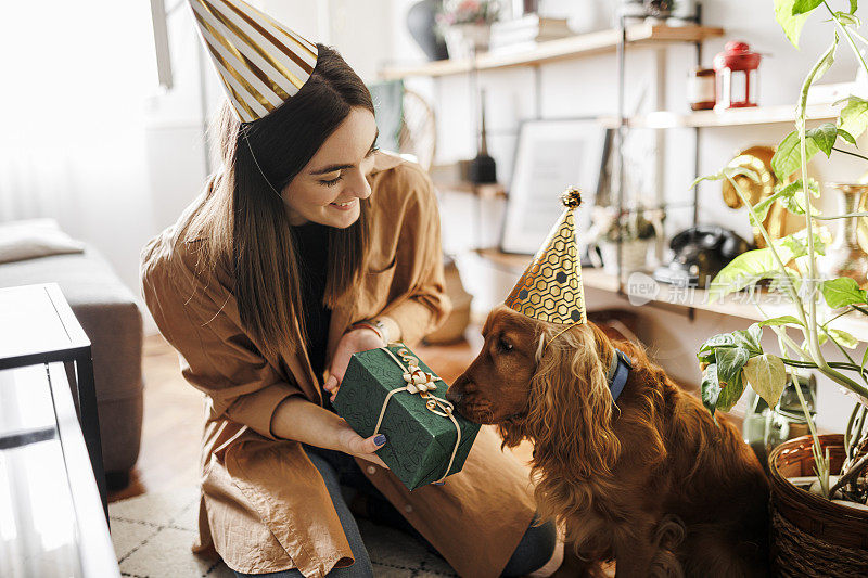 一个女人和她的狗在家里庆祝她的狗的生日。