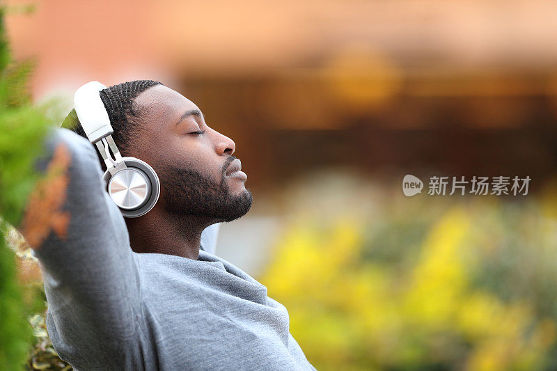 一个黑皮肤的男人在公园里听着音乐放松
