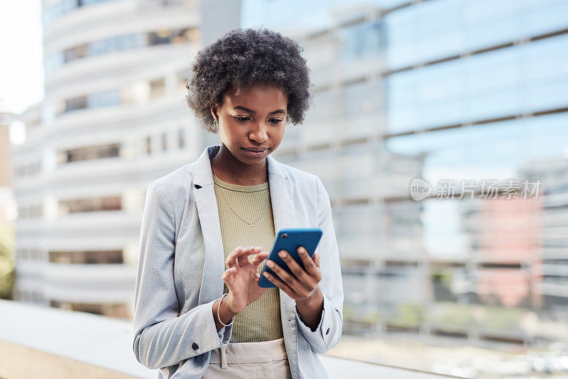一位企业家站在城里浏览社交媒体，查看工作邮件。利用无线技术在线app进行网络连接。非洲裔美国女商人在城市里打电话。