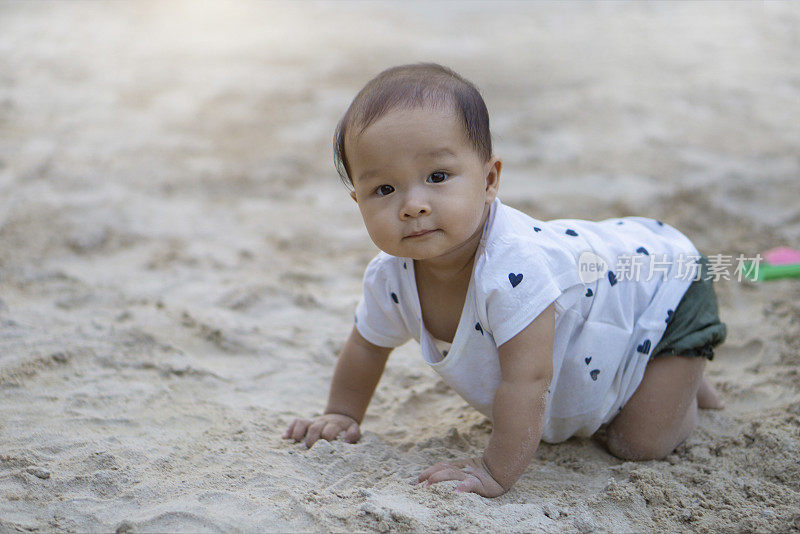亚洲蹒跚学步的婴儿泰国女孩玩沙子