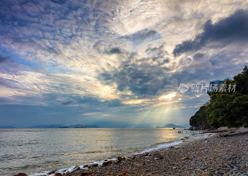 日落时，阳光洒在海面上，反射在岩石海滩上。