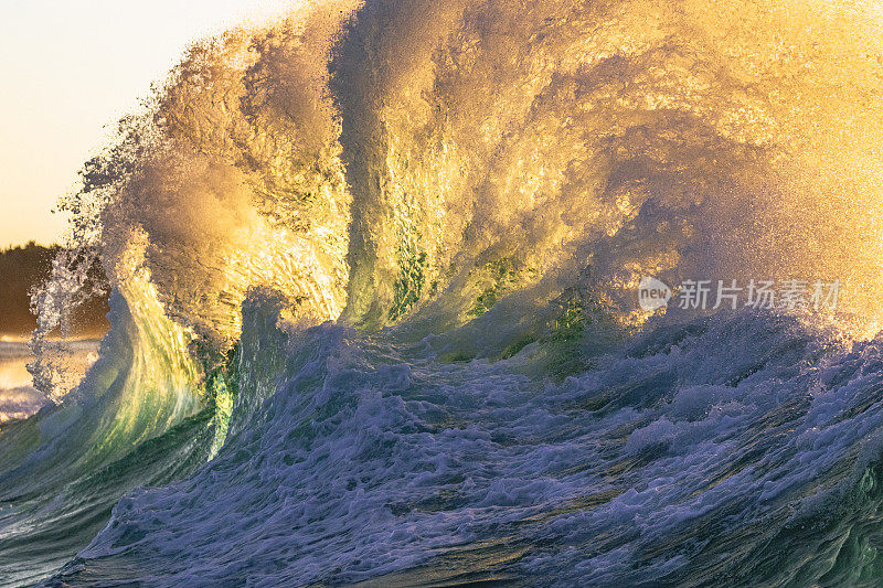 狂暴的海浪危险地冲破海岸，被明亮的金色晨光照亮