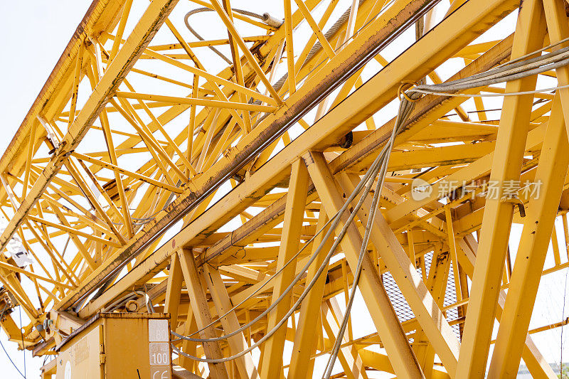 工地起重机上的橙色金属管道相互焊接的特写。用于建筑工地吊装大型货物，工业施工机械。