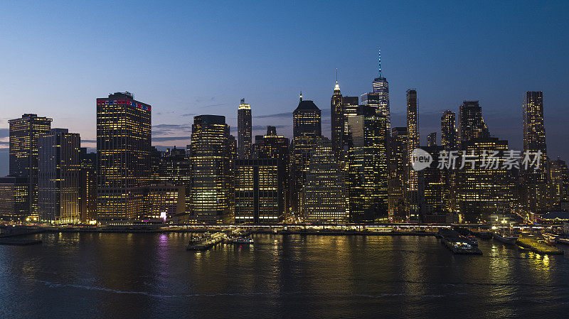 东河沿岸有渡船，夜间灯火通明。曼哈顿市中心有许多标志性的金融建筑:自由塔，一个世界贸易中心等。