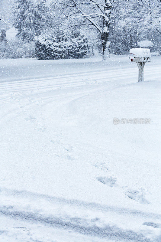 暴风雪留下的雪地脚印通向农村的邮箱