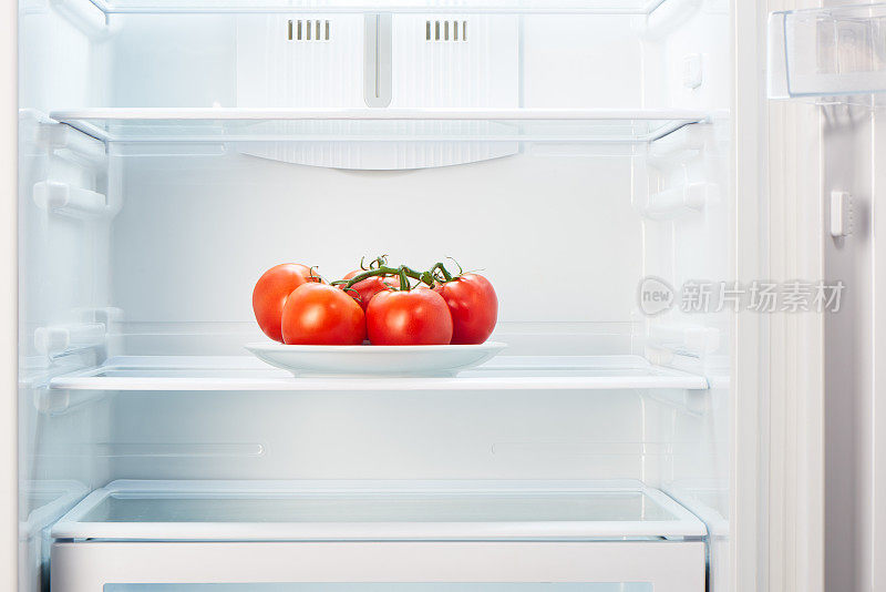 把西红柿支在空的白色盘子里放在冰箱里
