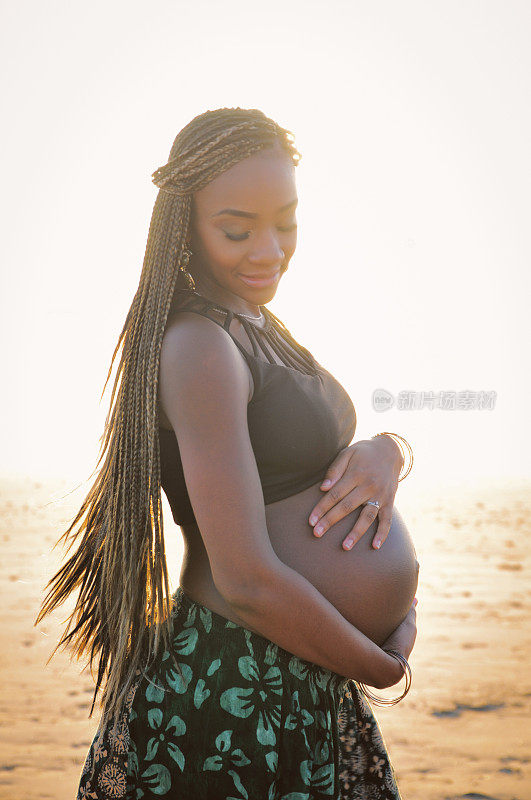 孕妇站在海滩上的侧视图