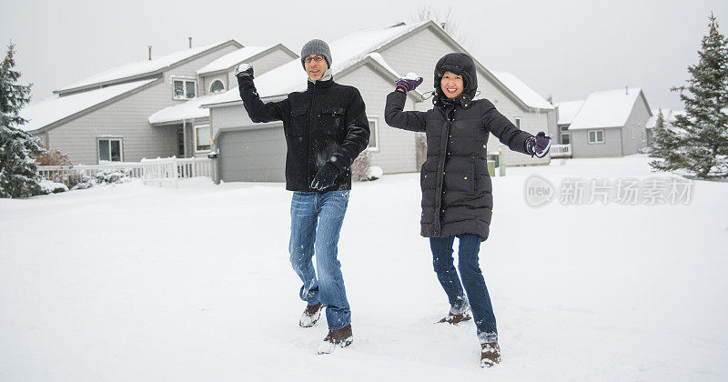 多民族的夫妇在户外的雪下玩耍