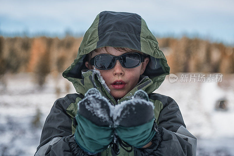 一个小男孩在冬天里扛着雪