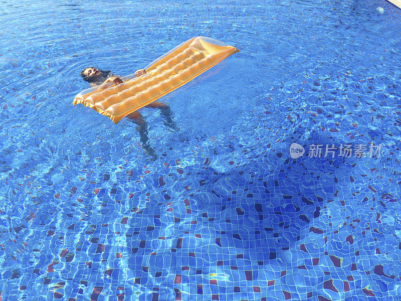 年轻女孩用充气床漂浮在游泳池里