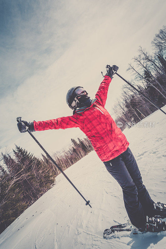在山上伸开双臂的女子滑雪者
