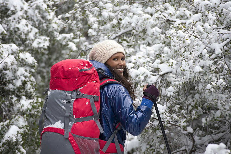 在白雪覆盖的森林里徒步旅行的女人。