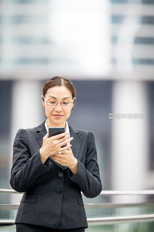 美丽的亚洲女商人在户外发短信