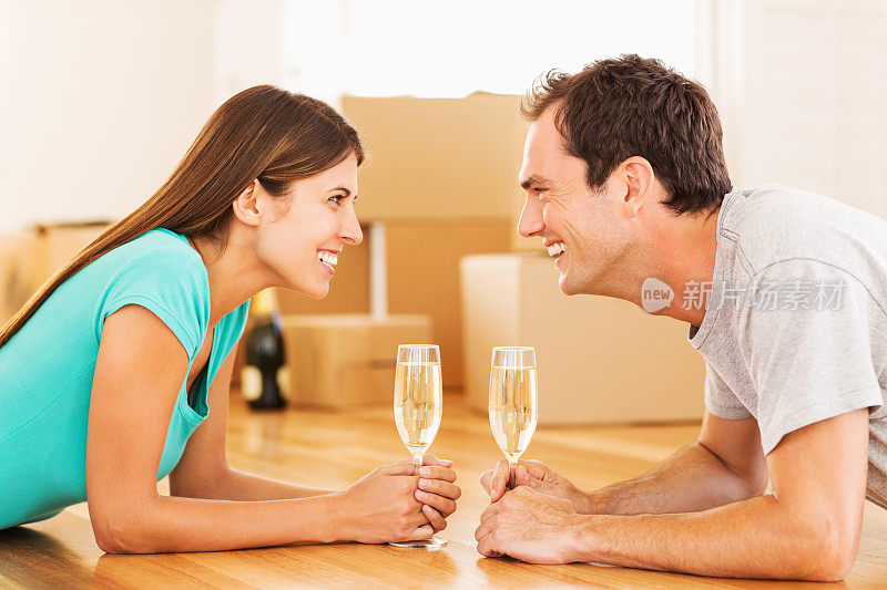 年轻夫妇在新房子里用香槟庆祝