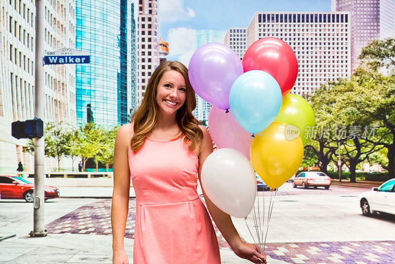 微笑的女人在城市里拿着气球