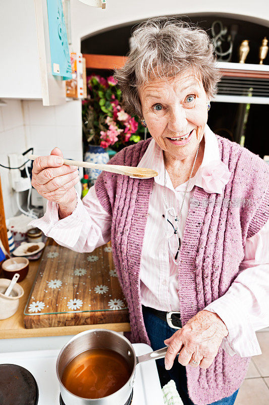 微笑的老妇人正在品尝她在家里做的东西