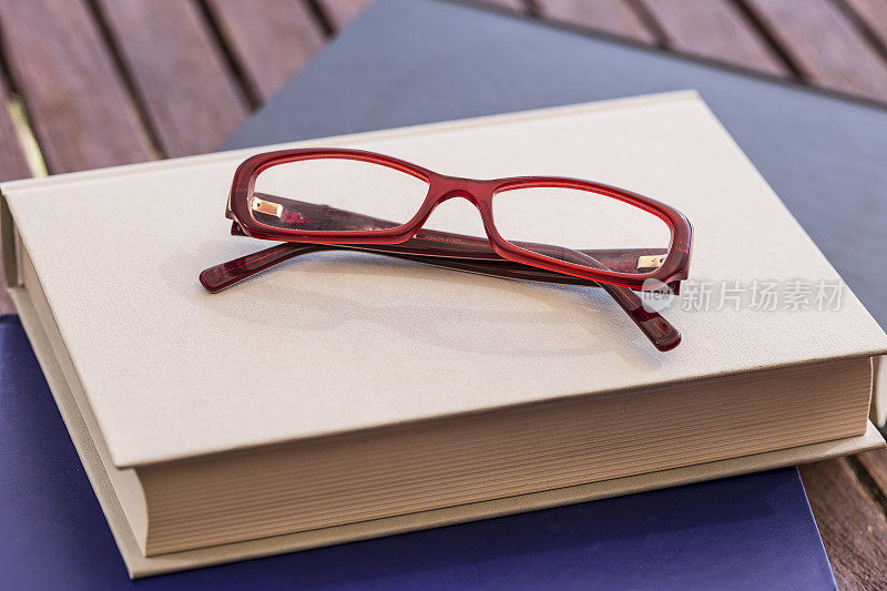 红色的眼镜在一本闭着的书上