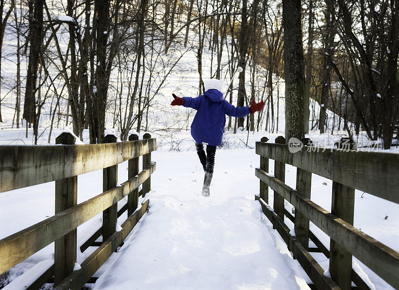 可爱的小男孩在雪中跳跃