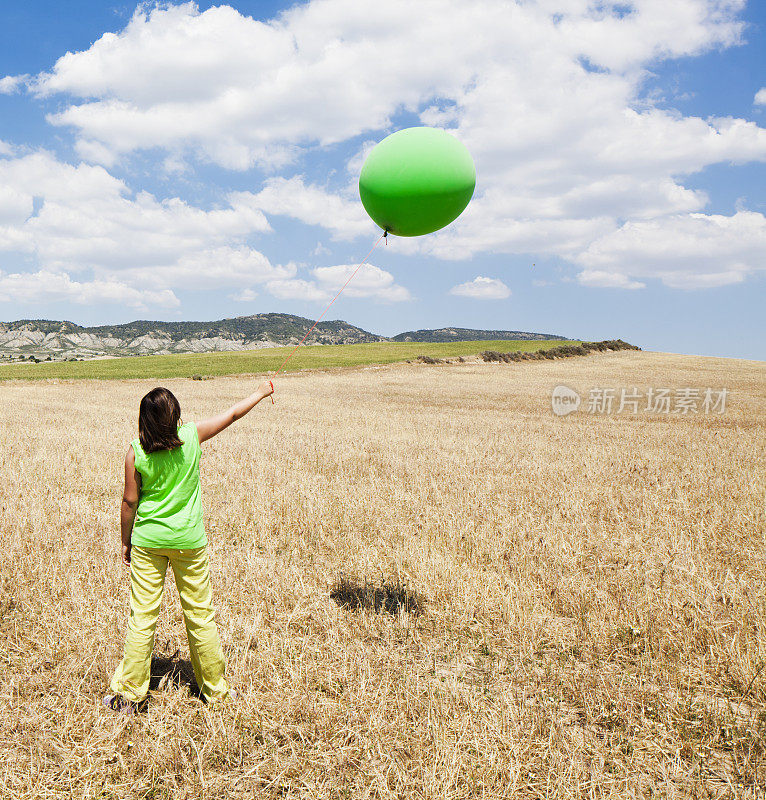女孩拿着绿色的大氦气球