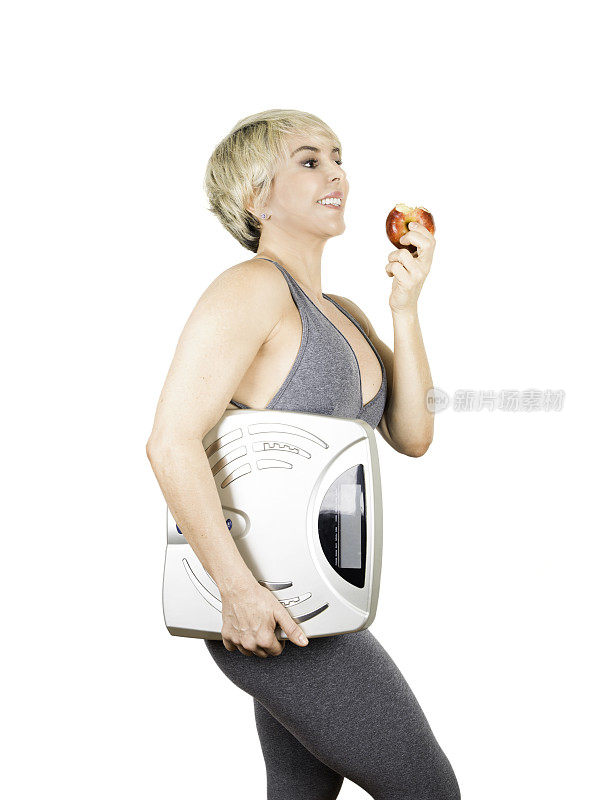 拿着磅秤准备吃苹果的健康女人。