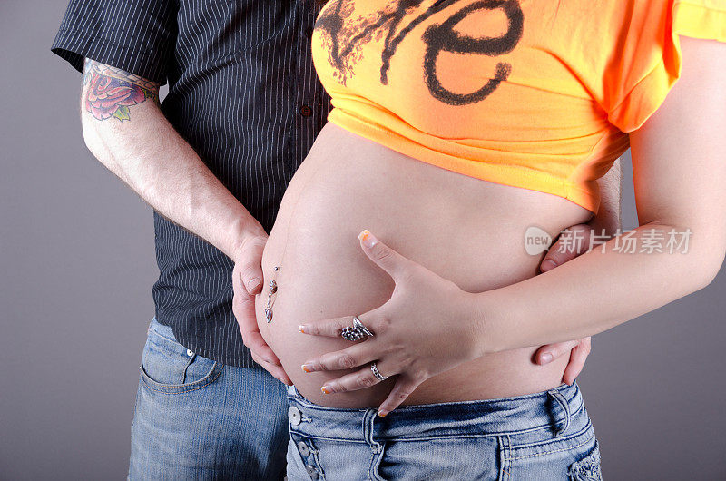 年轻的怀孕夫妇的腹部触摸。