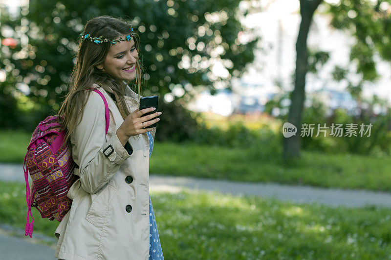 一个好女孩正在公园里散步，正在用手机写短信