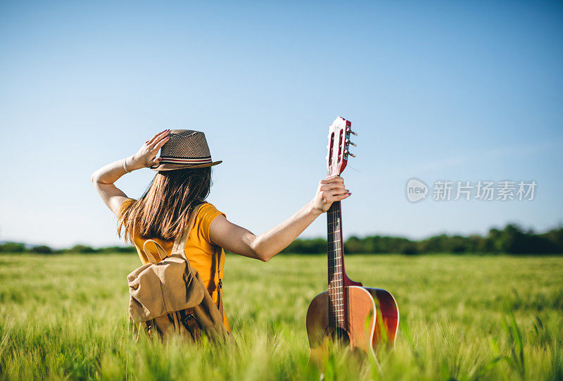 女吉他手在草地上欣赏日落