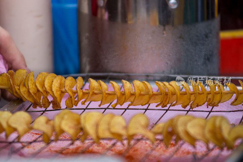 螺旋炸土豆丝在街头食品市场的摊位上出售，刚从油锅里出来。