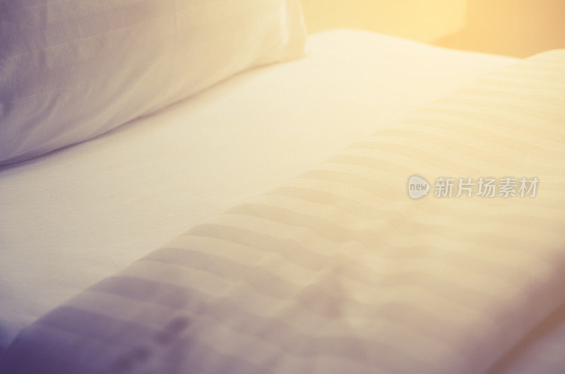 卧室里白色的床上放着白色的枕头