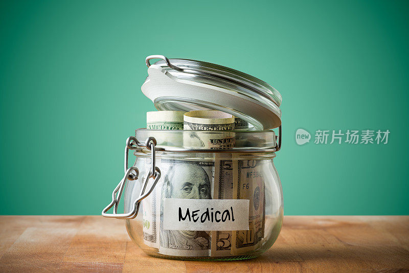 在绿色背景上孤立的玻璃罐中的美元。为医疗省钱的概念。