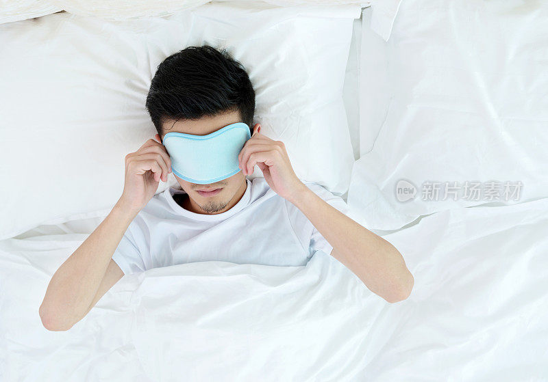 在床上戴着睡眠面罩的年轻人