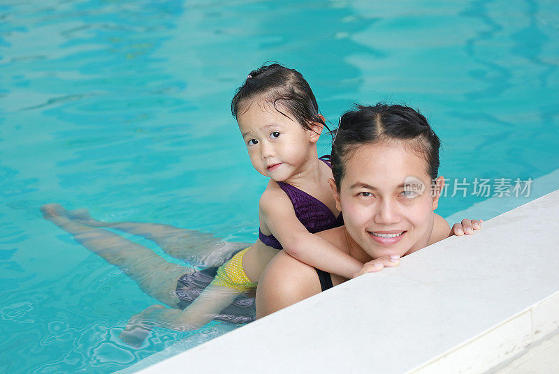 妈妈和小女孩在游泳池里的肖像。