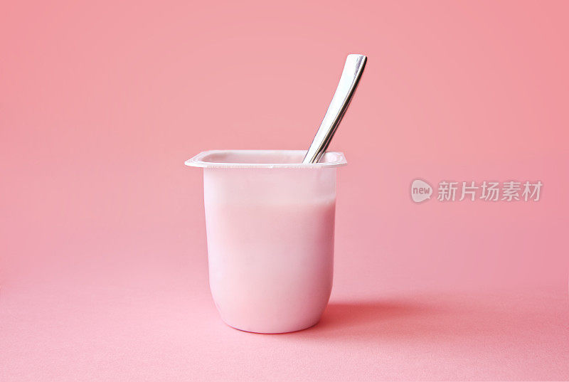 粉色背景的塑料杯草莓酸奶或布丁