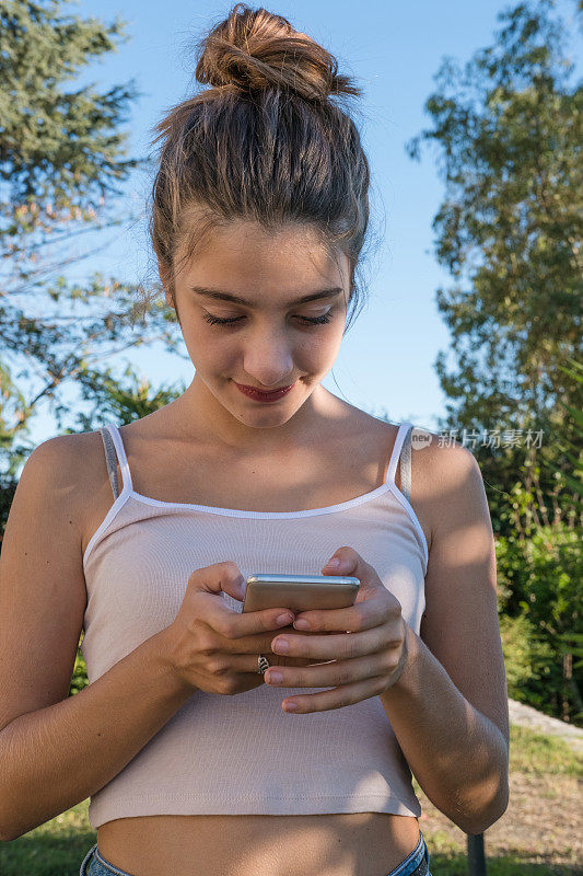 年轻的金发女孩用手机发短信