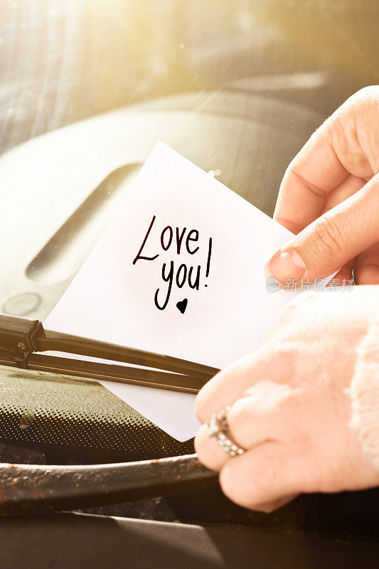 女性手放纸条“爱你!!”在汽车挡风玻璃上