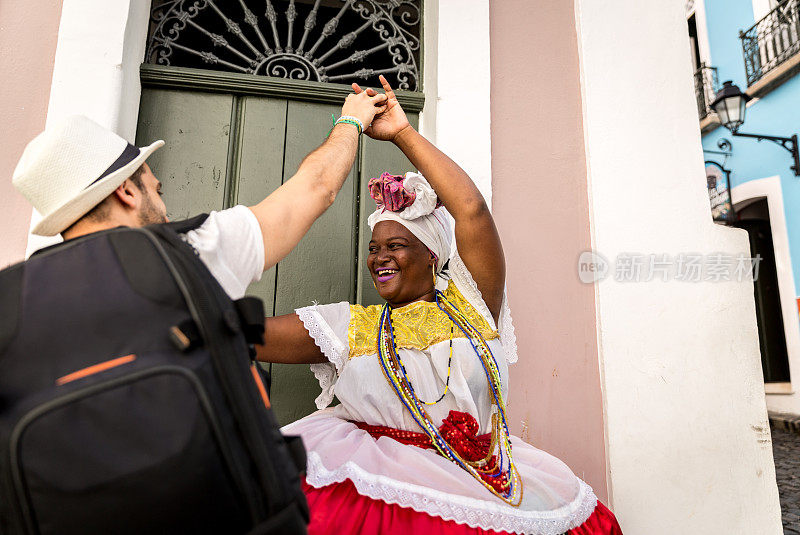 在巴西巴伊亚州萨尔瓦多的Pelourinho，游客与“Baiana”女子跳舞
