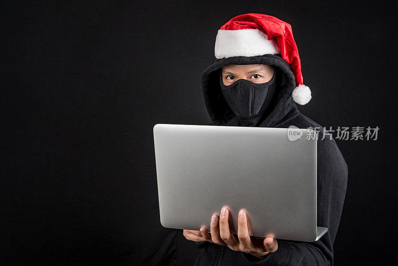 拿着笔记本电脑的神秘圣诞老人黑客