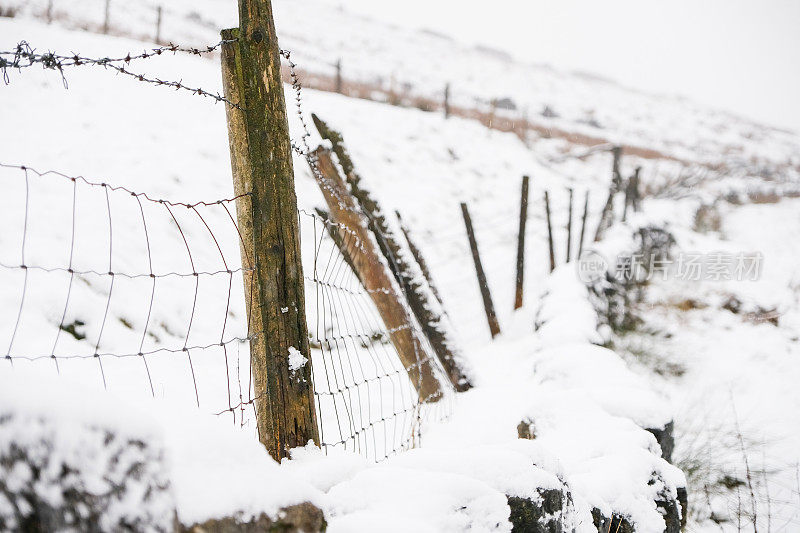 英格兰峰区国家公园，一个下雪的日子里，在萨德尔沃斯沼泽的木柱带刺铁丝网栅栏的特写