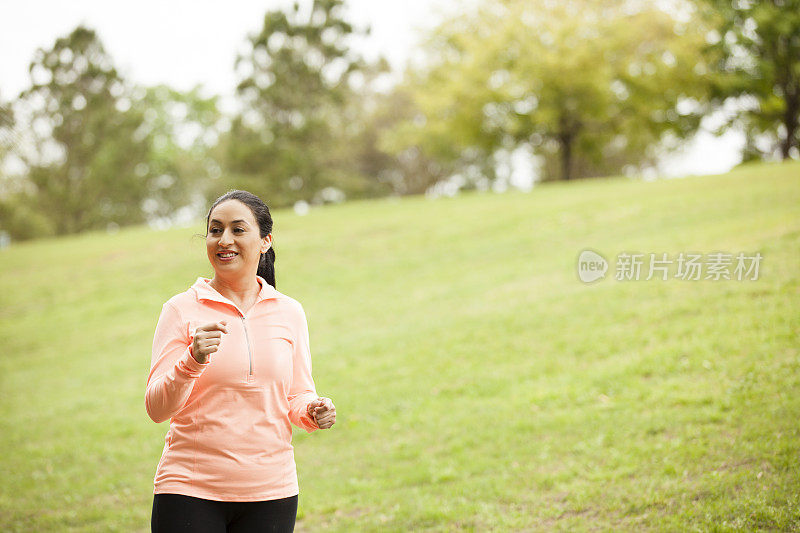 一位拉丁裔妇女在附近的公园里跑步。