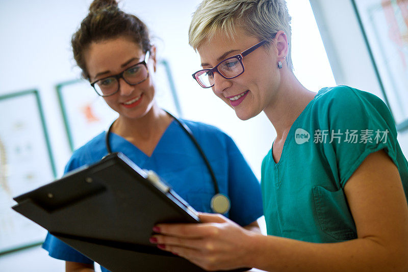近距离观察两个专业护士与眼镜检查病人文件在医生的办公室。