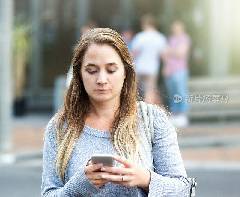 街上一位神情焦虑的妇女低头看手机