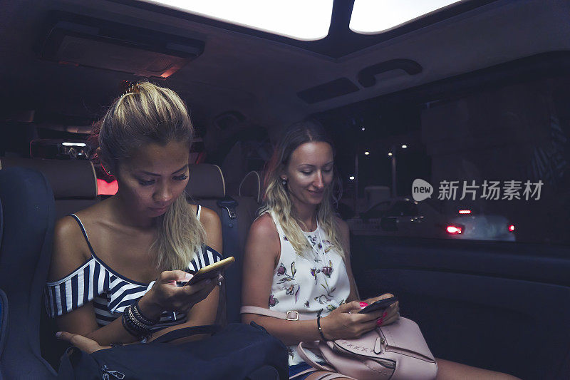 女性晚上在出租车上使用手机
