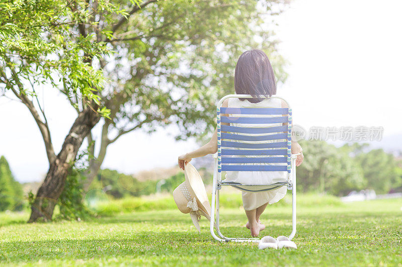 年轻女人坐在躺椅上做日光浴