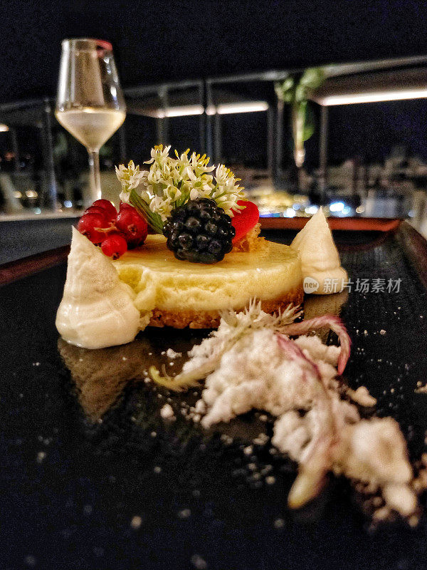 浆果芝士蛋糕和白葡萄酒是一个精致的餐厅晚餐设置